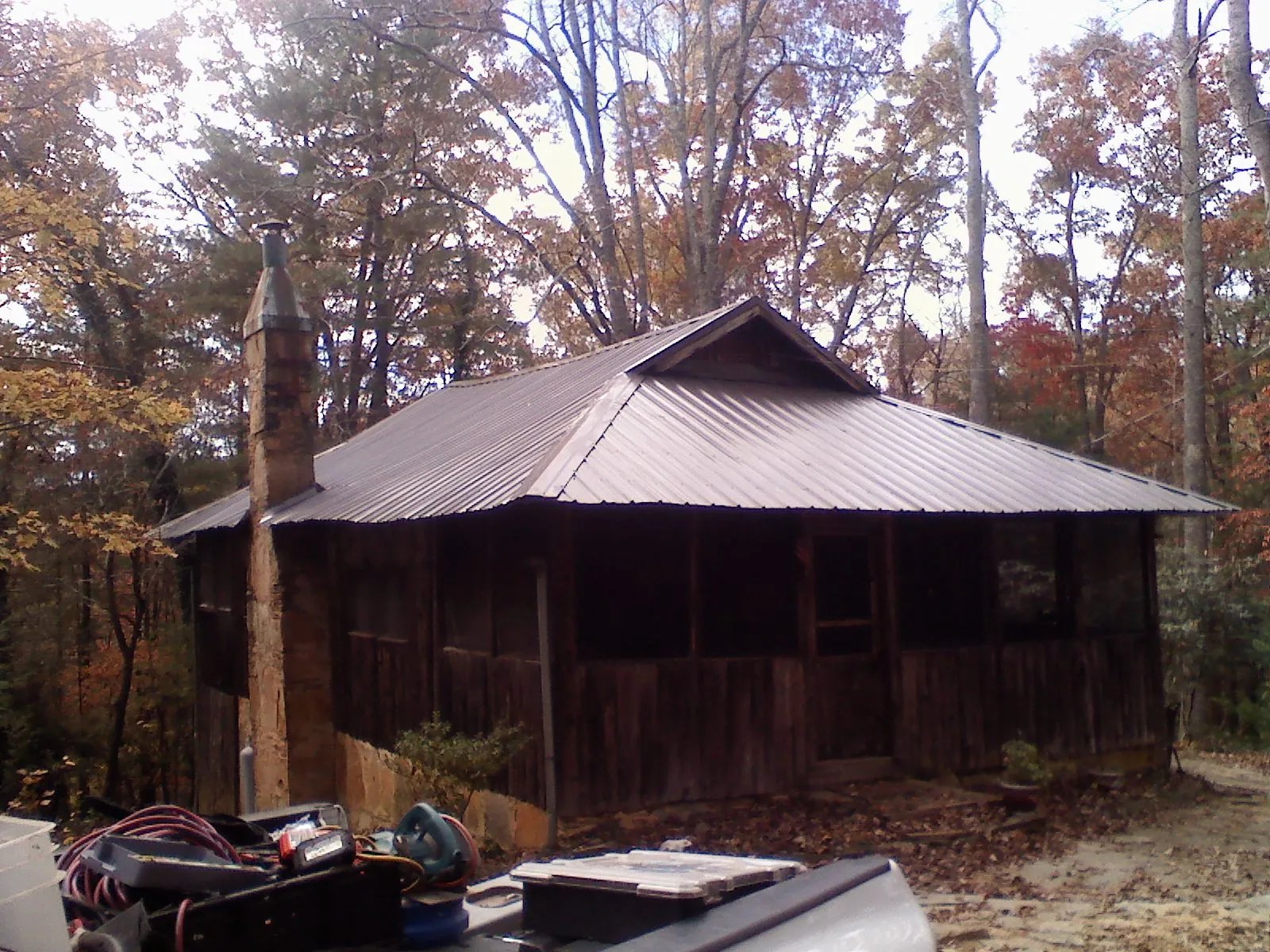 Brown metal hip roof on an old cabin with a stone chimney in Tropic