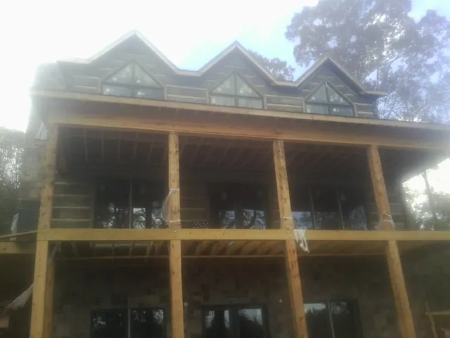Dormers and porch framing on a large log home under construction — Roof Coating work by our crew in Tropic