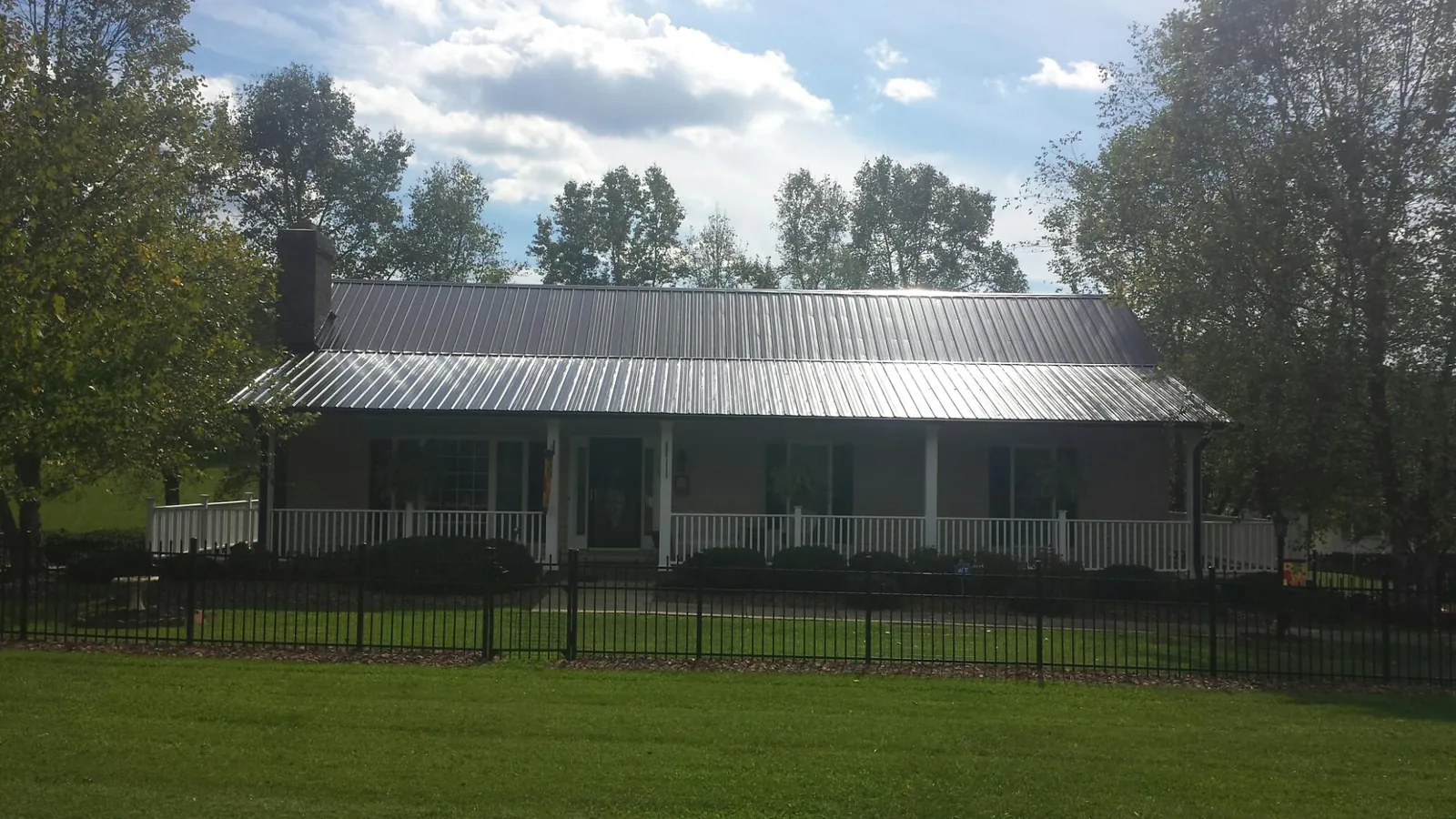 Gray metal roof on a brick ranch with a full width front porch — Gutter Guard Installation work by our crew in Tropic