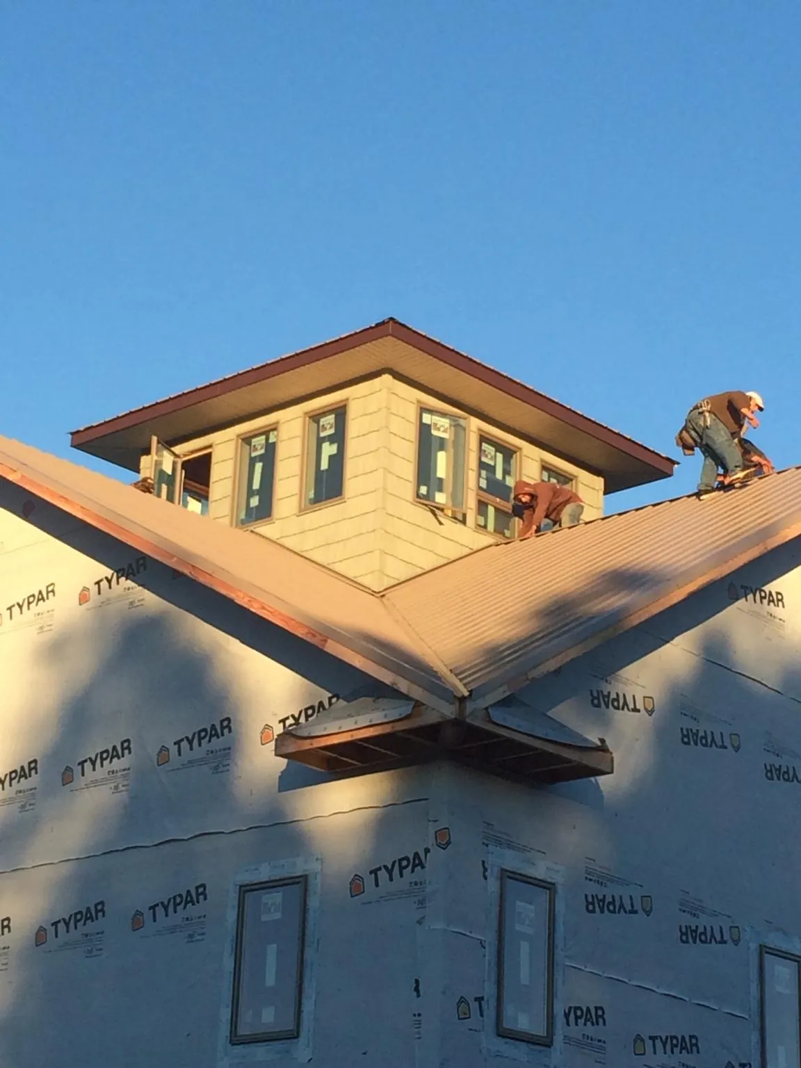 Roofers working around a rooftop cupola on a new metal roof at sunset — Roof Waterproofing in Tropic by Roofing Brothers